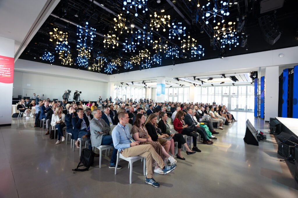 A large audience looks to a stage during a panel discussion. 