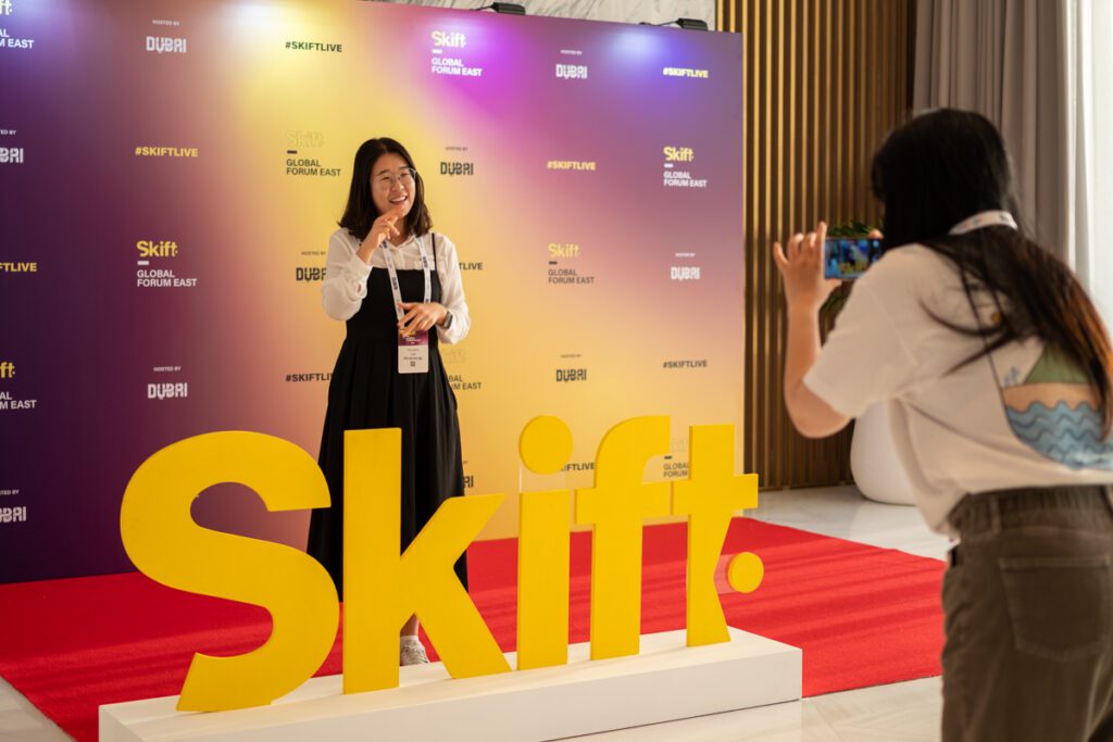 Two women taking pictures at the Skift Global Forum East media wall